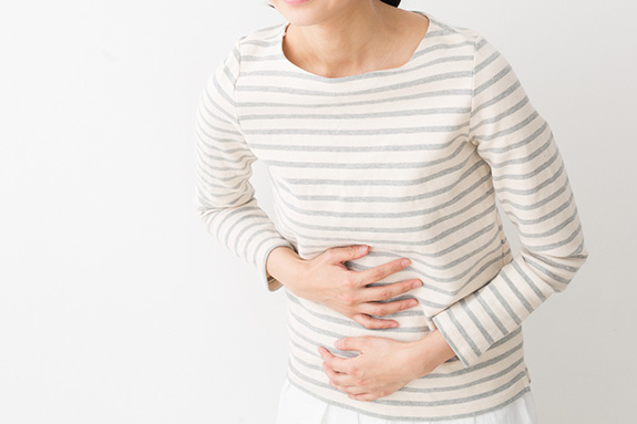 写真：胃を抑える女性
